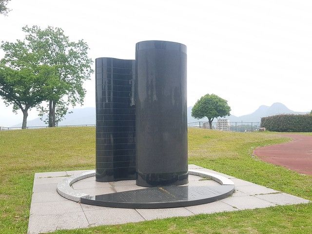 筑豐塵肺訴訟記念碑「我們不是捨石」,背景可見香春岳